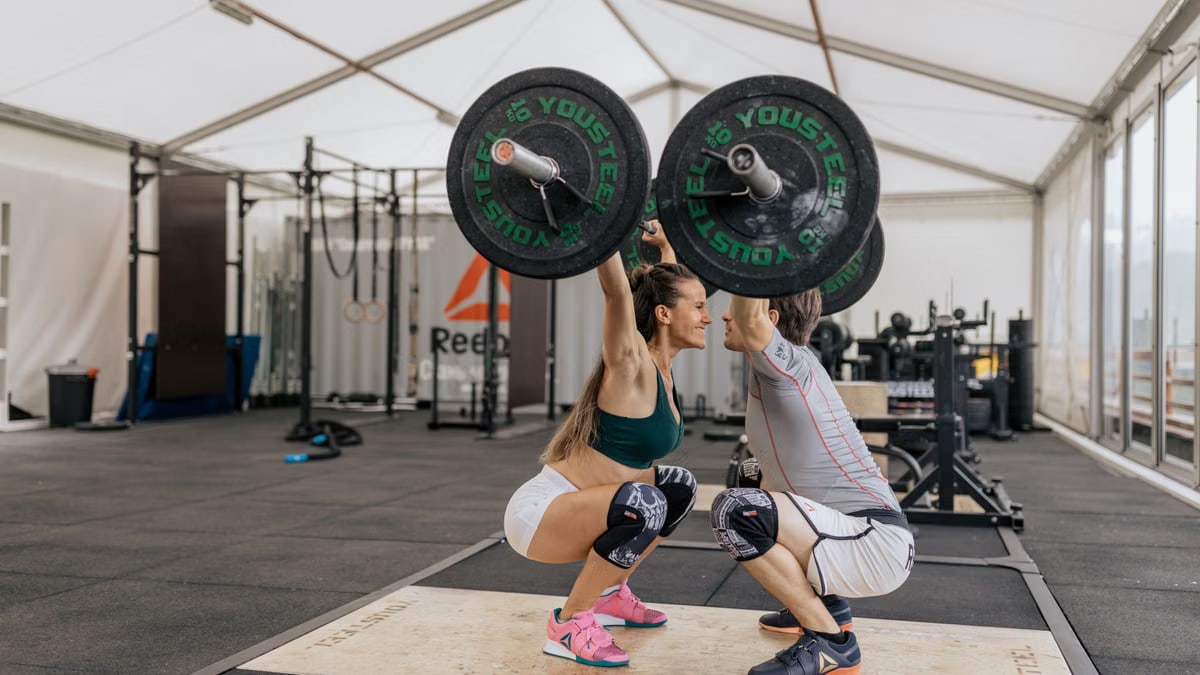A couple lifting weights together in a gym, promoting fitness and teamwork.
